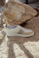 Zapatillas bajas de cuero color beige con detalles en animal print y suela blanca.