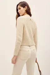 Cardigan de punto color beige, con escote en V y cierre frontal de botones, de mangas largas y corte corto.