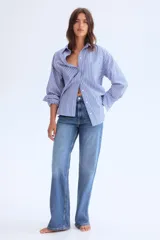 Jeans de cinco bolsillos en denim de algodón con leve stretch, de tiro alto y corte ajustado desde la cintura hasta el muslo, ensanchándose de la rodilla hacia abajo (bootcut). Presenta cierre y botón frontal.