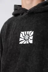 Buzo canguro con capucha, de calce oversize y efecto lavado gastado. Presenta un estampado gráfico central en color blanco y un pequeño parche con logo en el puño.