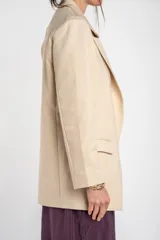 Blazer de algodón peinado, color beige, de calce al cuerpo con solapas clásicas y mangas largas.