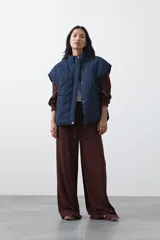 Chaleco acolchado de nylon con diseño capitoneado, cuello alto y cierre frontal con botones a presión. Presenta un calce amplio y versátil.
