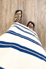 Vestido largo tejido a rayas horizontales azules y beige sobre fondo blanco, con mangas cortas y tajos laterales.