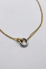 Collar de cadena fina en color cobre, con un dije colgante en forma de aro metálico bicolor que combina tonos plateados y cobrizos.