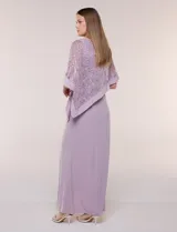 Vestido largo azul marino de seda fría, compuesto por una falda recta con tajo frontal y una capa superior superpuesta de encaje con lentejuelas bordadas, escote a la base y mangas tres cuartos acampanadas.