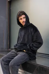 Canguro unisex negro de tela suave con capucha y bolsillo delantero tipo canguro. Tiene cordón ajustable en la cintura para usarlo largo o corto.