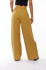 Pantalón de vestir color mostaza, de corte palazzo, con pinzas en la cintura y bolsillos laterales.