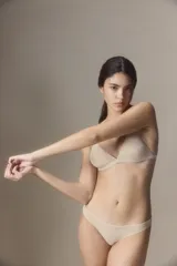 Corpiño tipo triángulo de diseño minimalista, confeccionado en tela suave color piel. Presenta breteles finos regulables y una banda elástica inferior para mayor soporte.