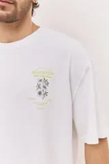 Remera oversize blanca de manga corta, con corte amplio y estampa gráfica pequeña en el pecho.