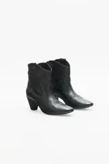 Bota corta de cuero negro con taco medio y punta fina. Presenta recortes grabados en el mismo material en el cuerpo de la bota.