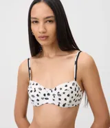 Top de bikini de microfibra color blanco con estampado de caracolas, caracoles y estrellas de mar negras. Cuenta con diseño de media copa, aro estructurado y breteles regulables con detalles metálicos.