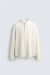 Camisa de corte regular fit confeccionada en tejido de algodón con textura cuadrillé. Presenta cuello solapa, manga larga con puños abotonados y cierre frontal con botonadura.