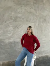 Sweater de punto color bordó, con cuello polo, cierre frontal parcial con botones y diseño de rombos en relieve en la parte frontal. Posee mangas largas con puños ajustados.