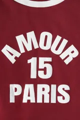 Remera de algodón color bordó con cuello redondo en contraste blanco y estampa frontal con la frase 'AMOUR 15 PARIS' en letras blancas.