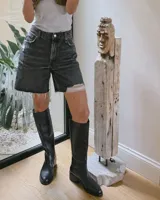 Bota de caña alta confeccionada en cuero vacuno gamuzado color verde oliva, con cierre lateral y taco bajo cuadrado.