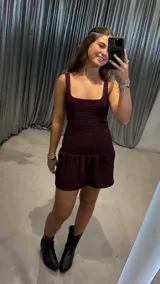 Vestido corto de color bordó con textura arrugada, escote cuadrado y falda con volado en el ruedo.