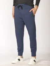 Pantalón de jogging color verde militar, corte slim, con puños elastizados en los tobillos y cordón ajustable en la cintura. Presenta un bolsillo lateral con cierre.