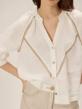 Camisa azul de lino con mangas 3/4, cuello redondo y detalles de ribetes en contraste.