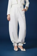 Pantalón de mujer color blanco, de corte amplio y silueta fluida, con cintura definida y puños ajustables con tiras para atar en los tobillos.