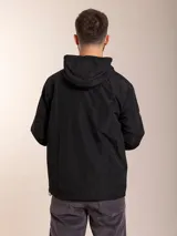 Campera de nylon con capucha, cierre frontal y forro de red. Presenta un diseño minimalista en color beige con detalles en negro.