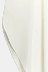 Pantalón fluido de tiro alto en color blanco, con pinzas delanteras, cintura elástica en la espalda y perneras anchas con aberturas laterales pronunciadas.