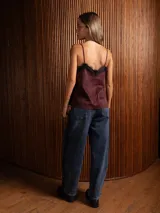 Top de breteles finos estilo camisola, confeccionado en material símil gamuza color negro, con detalle de encaje en el escote y costura vertical frontal.