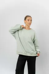 Buzo oversize de algodón frizado color beige, con cuello redondo, puños y cintura tejidos. Presenta un bordado pequeño de Snoopy en el frente.