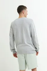 Sweater verde oscuro de tejido de punto, con escote en V y mangas largas.