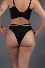 Bombacha de bikini negra tiro medio confeccionada en lycra con detalle de tiras cruzadas en la cintura.