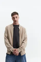 Campera tejida de punto color beige, con cuello rib, puños y bolsillos laterales.