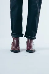 Bota de caña media confeccionada en cuero negro con acabado brillante, diseño de silueta limpia, puntera cuadrada y taco cuadrado de altura media.