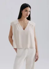 Blusa color naranja, sin mangas, con escote en V y detalle de frunce en los hombros.