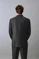 Blazer de corte regular confeccionada en lana de origen italiano, con diseño a cuadros sutiles. Presenta cuello con solapas de pico, cierre frontal de botones, bolsillos de solapa en la cadera y bolsillo de vivo en el pecho.