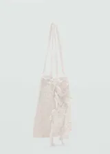Bolso tipo saco color blanco, confeccionado en tejido de crochet con detalles de flores aplicadas, asas cortas de mano y diseño sin cierre.