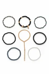 Set de múltiples pulseras elastizadas de cuentas y abalorios de distintos materiales, incluyendo eslabones dorados y dijes colgantes.
