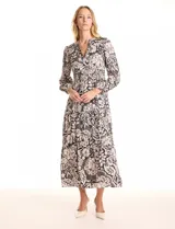 Vestido maxi de gasa estampada en blanco y negro, marca Julia Jordan. Escote en V, hombros con fruncidos, mangas largas amplias con puños elastizados. Cintura con faja ancha de punto smock y falda escalonada con vuelo. Cierre invisible y botones metálicos en la espalda. Forro interno a tono.