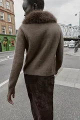 Chaqueta de punto color marrón con cuello de solapa desmontable en pelo sintético. Presenta cierre frontal con botones, manga larga y terminaciones en rib.