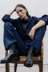 Bota corta de cuero negro con cierre frontal con cremallera y suela de goma.