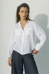 Camisa de manga larga con cuello camisero y cierre frontal con botones. Diseño a rayas verticales color beige y blanco, con dos bolsillos de parche en el pecho.
