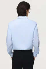 Camisa de vestir slim fit con diseño a rayas celestes y blancas, cuello inglés, cierre frontal de botones y mangas largas con puños abotonados.