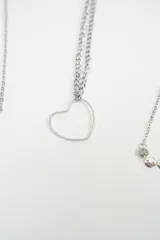 Set de cuatro pulseras de cadena fina en color plateado con diferentes diseños: una con dijes de corazones, una con un dije de corazón grande, una con dijes circulares pequeños y una con eslabones en forma de corazón.