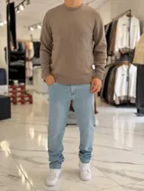 Buzo de hilo color beige claro, con cuello redondo y diseño clásico de manga larga.
