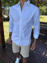 Camisa de manga larga color blanco, de corte clásico y cierre frontal con botones.