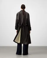 Gabardina larga de mujer, color marrón oscuro, con efecto encerado. Presenta un diseño cruzado con cuello solapa, cierre frontal con botones, cinturón a juego y bolsillos laterales.