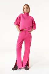 Pantalón de jean fucsia de pierna ancha con corte lateral acordonado en el bajo y detalle de tela roja en el lateral.