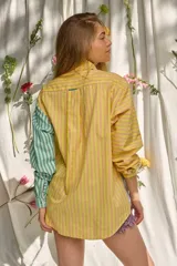 Camisa de manga larga con diseño patchwork de rayas en tonos verde, lila, amarillo y azul. Cuenta con cuello camisero, cierre frontal con botones y un bolsillo en el pecho con el logotipo bordado "pur".