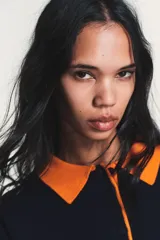 Jersey de punto de manga larga con cuello tipo polo en color naranja a contraste. Presenta cierre frontal con botones y diseño de corte holgado.