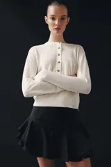 Shorts de tiro medio confeccionado en mezcla de viscosa, con diseño de volantes en el bajo y cierre lateral con cremallera oculta.