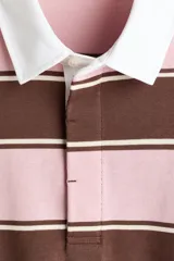 Remera tipo polo de manga larga con diseño a rayas horizontales en tonos rosado y marrón, con cuello blanco de sarga y cierre frontal con botones ocultos.