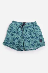 Short de baño celeste con estampado de hojas pequeñas en tonos verdes y blancos. Cuenta con cintura elástica con cordón ajustable, bolsillos laterales y un parche circular con logo en la parte inferior.